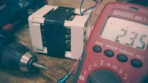 Benning multimeter reading 235 volts beside a drill and relay