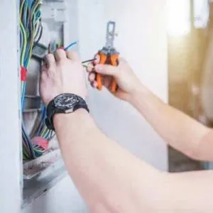 Electrician wiring a panel with pliers among colored cables