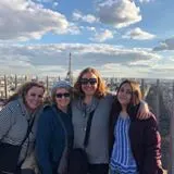 Four women posing on a rooftop with the Eiffel Tower behind them