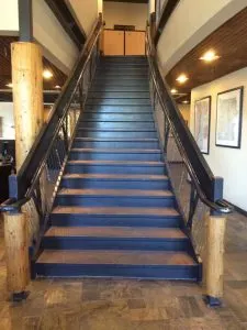 Wide interior staircase with dark metal railings and blue treads