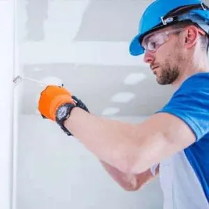 Worker in hard hat and safety glasses smoothing a wall