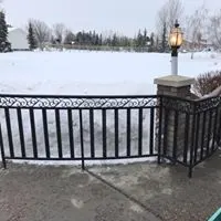 Black wrought-iron railing along a snowy patio with a lamp post