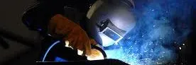 Close-up of a welder joining metal with a glowing blue arc