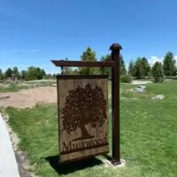 Rusted metal Muirwood sign with tree design on wood post in a grassy field