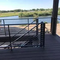 Black horizontal cable railing on a composite deck overlooking a river