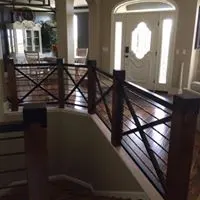 Dark wood and metal interior stair railing with horizontal bars in a home foyer