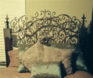Ornate scrolled wrought iron headboard behind decorative pillows