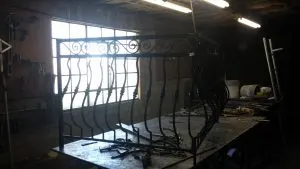 Custom wrought iron balcony railing under fabrication in a metal shop