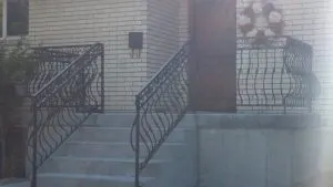 Close-up of ornamental wrought iron porch railing with scroll and baluster detail
