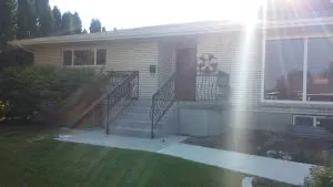 Brick home entrance with custom scrolled wrought iron porch railing and steps