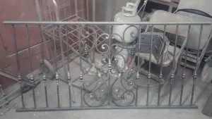Iron railing section with scrollwork detail resting in the shop