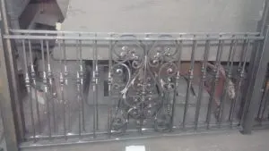 Decorative wrought iron railing panel with scrollwork in the fabrication shop