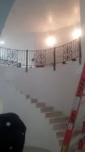 Curved black wrought-iron railing on an interior balcony above a tiled staircase