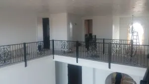 Black wrought-iron balcony railing with scrollwork panels on an interior second floor