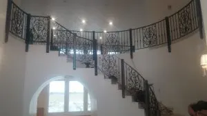 Ornate black scrollwork iron railing along a curved balcony above an arched window