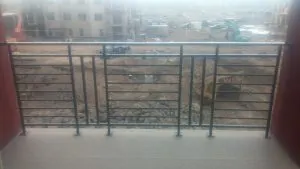 Black horizontal-bar metal balcony railing overlooking a construction site