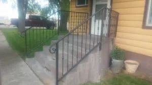Black metal handrail with knuckle-detail balusters on concrete front steps