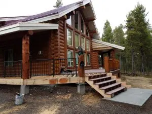 Log home with metal porch railing and deck framing under construction