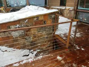 Stainless steel cable railing around a snow-covered deck opening