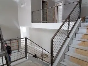 Stainless steel horizontal-bar and cable stair railing at an interior landing
