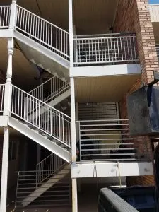 White painted metal exterior stair railings on a multi-level brick apartment building
