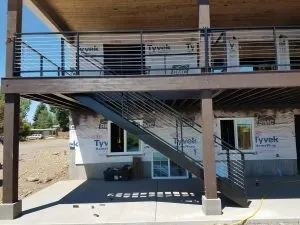 Black horizontal-bar deck railing and open stairs on a house under construction