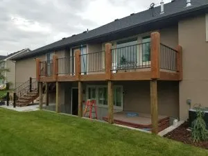 Black metal deck railing with vertical balusters and stairs on an elevated wood deck