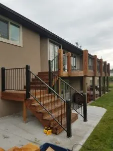 Wood-post deck with black metal balusters over a patio and covered hot tub