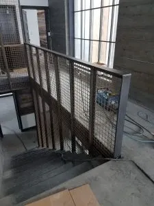Industrial steel stair guardrail with expanded-metal mesh panels indoors