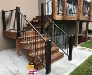 Black metal stair railing with twisted balusters on a wood deck staircase