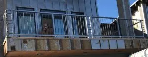 Galvanized steel balcony railing with vertical pickets on a metal-clad building
