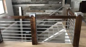 Wood-post railing with horizontal metal bar infill overlooking a stairwell