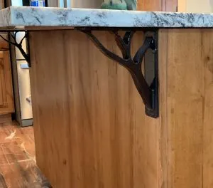 Decorative cast iron tree-branch corbel bracket supporting a marble countertop