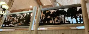 Metal wildlife scene panels set in log railing on a cabin loft overlook
