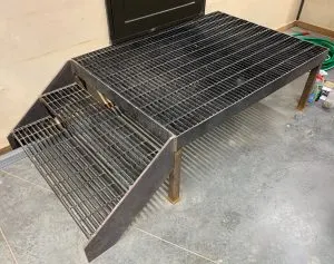 Custom steel grate platform with steps and metal frame on a concrete floor