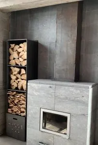 Modern tile fireplace with a steel firewood storage rack labeled Hygge Hus
