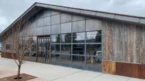 Exterior of a weathered wood and metal-clad commercial building with steel-framed glass doors