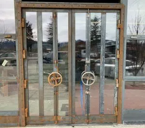 Steel-framed glass entry doors with cast iron handwheel latch mechanisms