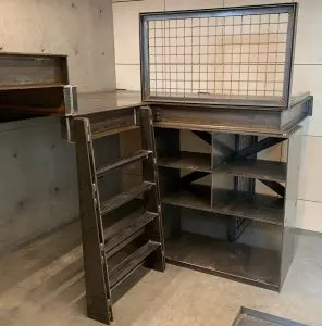 Fabricated steel storage cabinets with mesh top, cubby shelves, and ladder in a concrete room