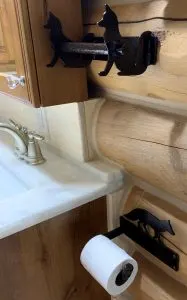 Fox-themed metal towel bar and toilet paper holder on a log cabin bathroom wall