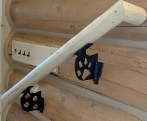 Log handrail mounted on black metal brackets with paw-print cut-outs