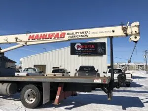 MANUFAB Quality Metal Fabrication boom truck parked outside the metal shop in winter