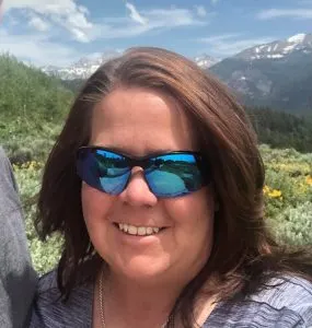 Portrait of a smiling woman wearing sunglasses in front of mountains