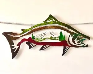 Metal wall art of a fish with a mountain and pine tree scene cut into it
