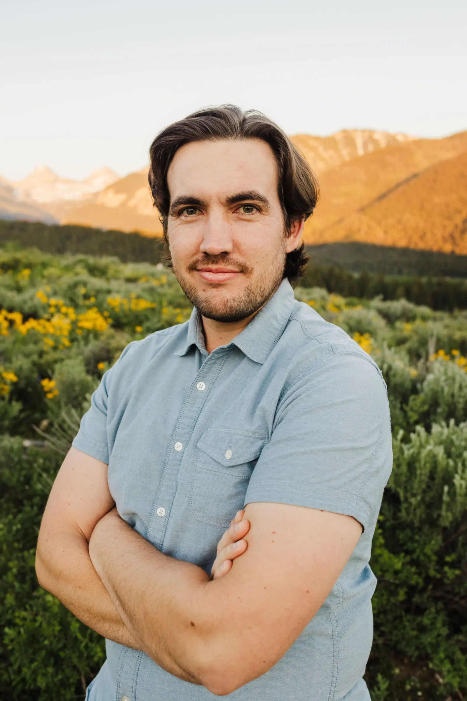 Portrait of a man with crossed arms in front of mountains at sunset